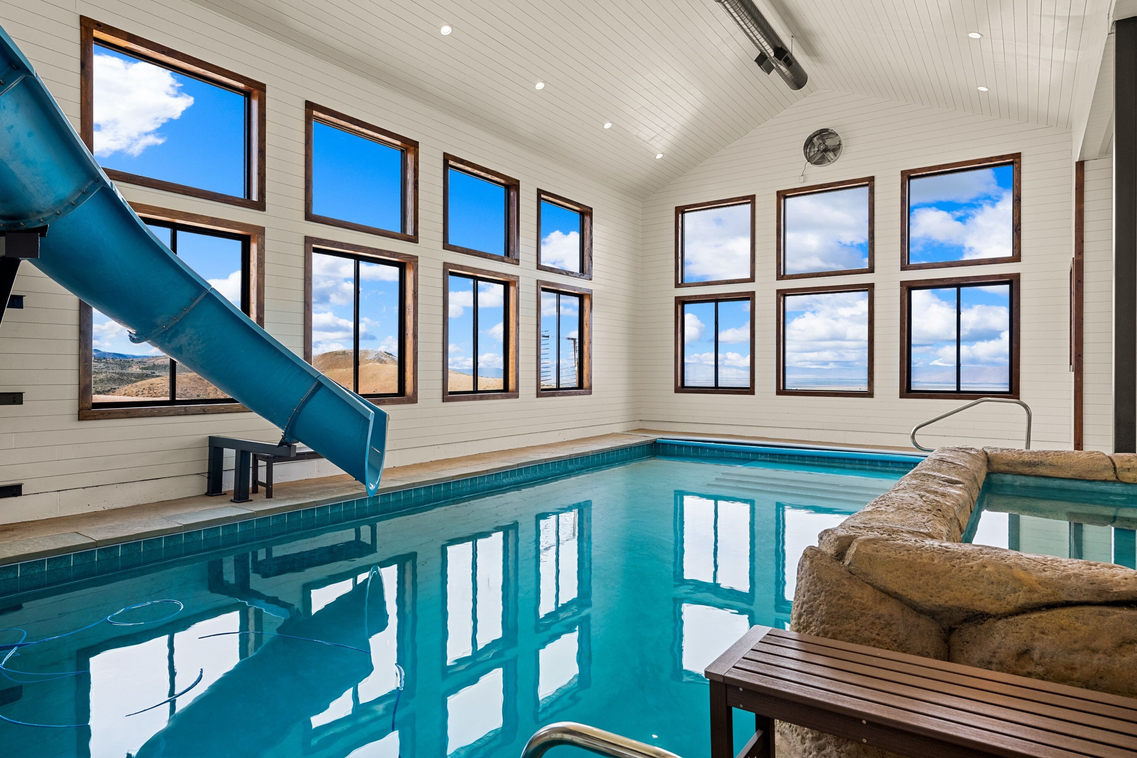 An indoor swimming pool with a slide, large windows, and a view of the desert landscape.