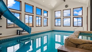 Una piscina interior con tobogán, ventanas amplias y vistas al paisaje desértico.