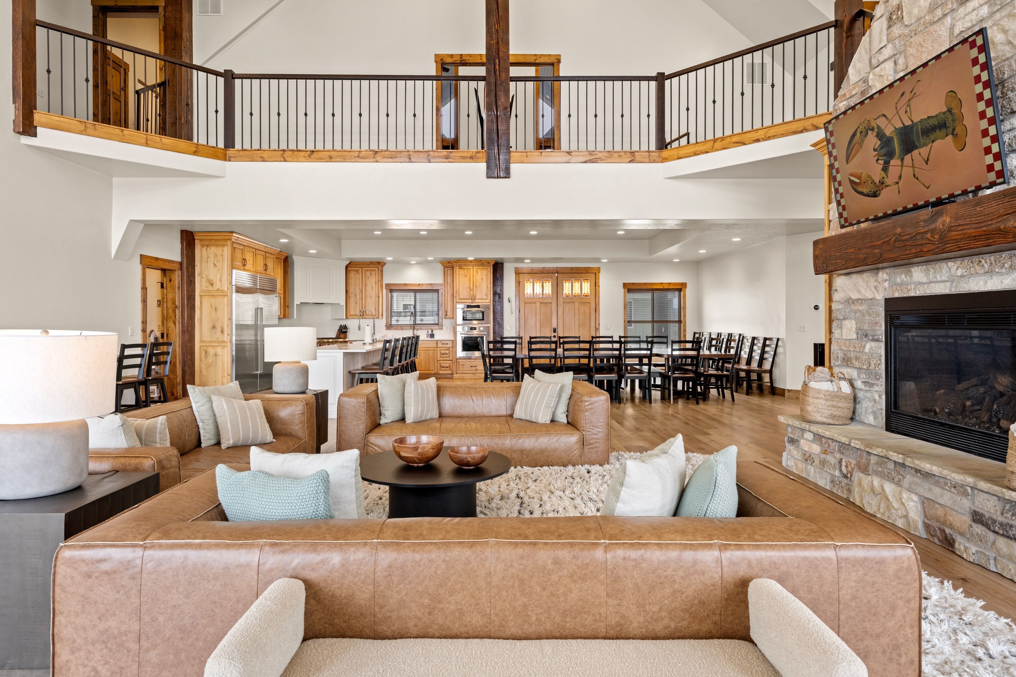 A spacious living area with a high ceiling, a fireplace, and a dining area with multiple chairs.