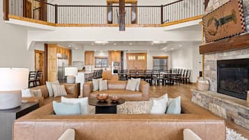 A spacious living area with a high ceiling, a fireplace, and a dining area with multiple chairs.