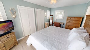 A bedroom with a bed, a dresser, a vanity, a television, and a ceiling fan. - Sandpiper Cove 0013 3 Bedroom Villa (Destin)