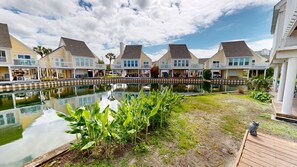A waterfront property with multiple-story buildings, a central pool, and a wooden deck. - Sandpiper Cove 0013 3 Bedroom Villa (Destin)