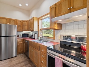 A modern kitchen with wooden cabinets, stainless steel appliances, a window, and a tiled backsplash. - Thulite Chalet - 20-ncd0315 2 Bedroom Home (Estes Park)