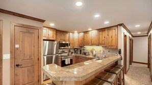 Cucina con mobili in legno, elettrodomestici in acciaio inossidabile, piano di lavoro in marmo e una panca integrata.