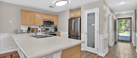 A kitchen with wooden cabinets, stainless steel appliances, and a marble countertop.