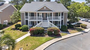 A two-story house with a front porch, a driveway, and a parking lot. - 77b Coastal Fairway 3 Bedroom Condo (Pawleys Island)