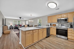 A modern kitchen with wooden cabinets, stainless steel appliances, and a central island. - 77b Coastal Fairway 3 Bedroom Condo (Pawleys Island)