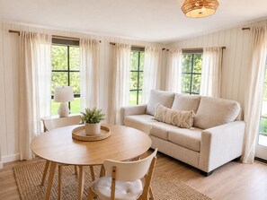 A living room with a round wooden table, beige sofa, and a lamp. - 4/3 Heated Pool/Hot Tub, Close to AMI Beach and IMG (Bradenton)