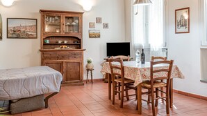 Een gezellige kamer met een bed, een eettafel met stoelen, een houten kast en een televisie.