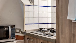Een keuken met een magnetron, fornuis en een betegelde spatwand.