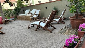 A rooftop patio with wicker lounge chairs, a small table, and potted plants. - Domus Socolatae Cocoa Journey  (Follonica)