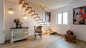 A modern interior with a staircase, a console table with decorative items, and a painting on the wall. - IL GIARDINO SEGRETO (Castelfidardo)