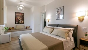 A modern hotel room with a large bed, bedside tables, a small refrigerator, and artwork on the walls. - IL GIARDINO SEGRETO (Castelfidardo)