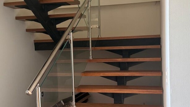 Una escalera moderna con barandillas de vidrio y escalones de madera.