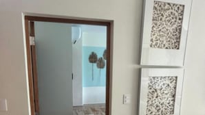 Una habitación con puerta de madera, piso de mármol y dos paneles decorativos en las paredes.