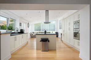 A modern kitchen with white cabinets, a central island, and a stainless steel trash can.