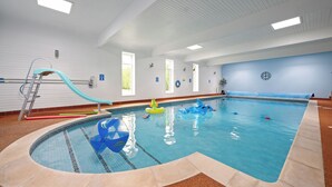 An indoor swimming pool with a slide, a ladder, and inflatable toys.