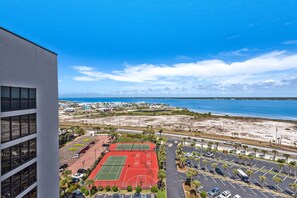A high-rise building overlooking a sports complex with tennis courts and a parking area. - ☀️🌴Beachfront Penthouse w/ Panoramic Views | Pool | Navarre Towers 1202 (Navarre Beach)