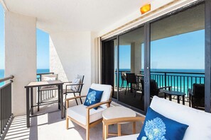 Een balkon met uitzicht op de oceaan, voorzien van een bank, stoelen en een tafel.
