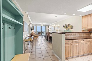 Een ruime keuken met een eetgedeelte en uitzicht, een bord met de tekst 'BEACH HOUSE'.