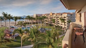 Un resort con piscina, palme e vista sull'oceano.