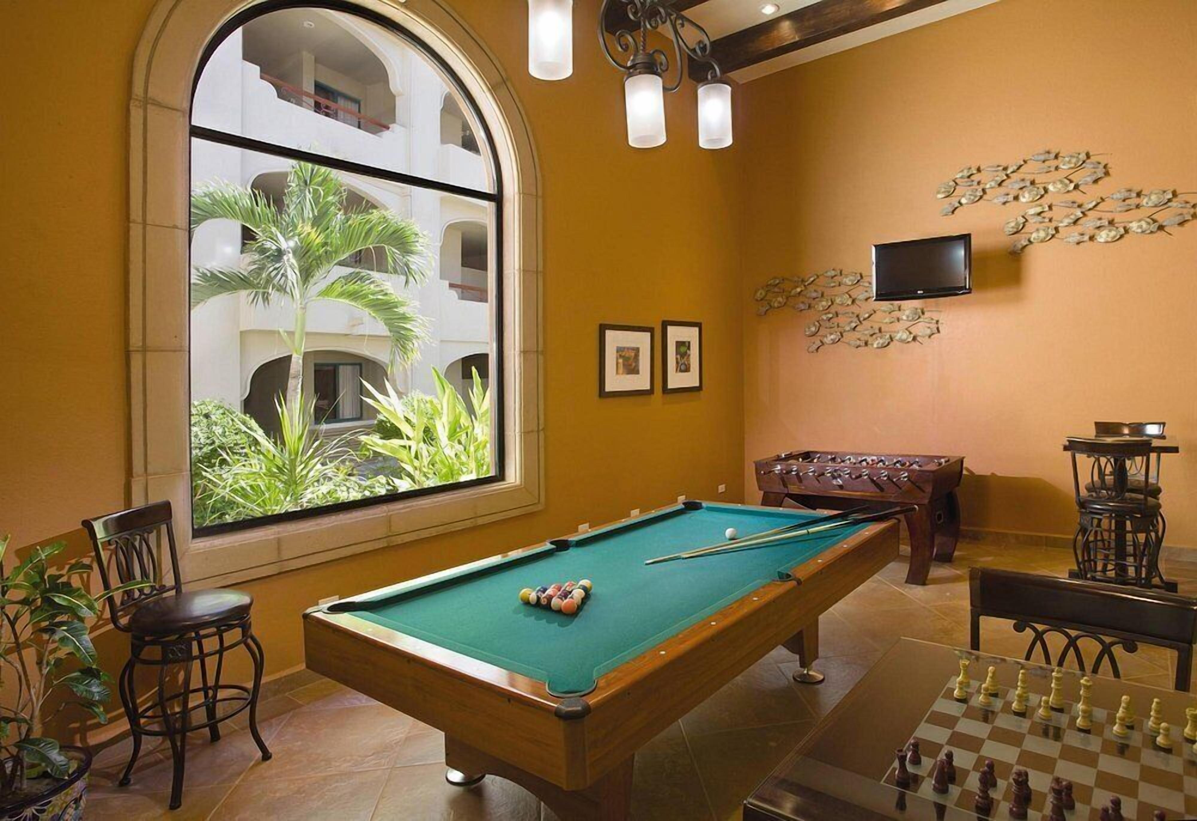 A pool table with a green felt surface, a chessboard, and a billiards table with balls.
