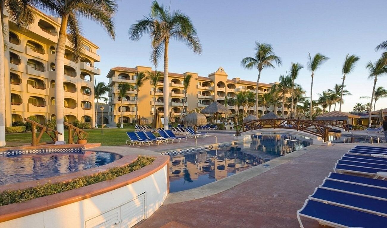 Ein Hotel mit mehreren Balkonen, einem Pool und Palmen.