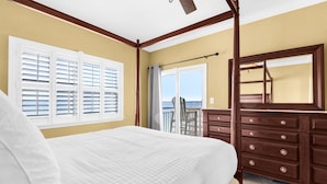 A bedroom with a bed, a dresser, a ceiling fan, a window with blinds, and a view of the outdoors. - ☀️🩴Stunning Sound Front Views | Community Pool | Walk to Beach | Baywatch E5 (Pensacola Beach)