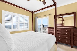 A bedroom with a bed, a dresser, a ceiling fan, a window with blinds, and a view of the outdoors. - ☀️🩴Stunning Sound Front Views | Community Pool | Walk to Beach | Baywatch E5 (Pensacola Beach)