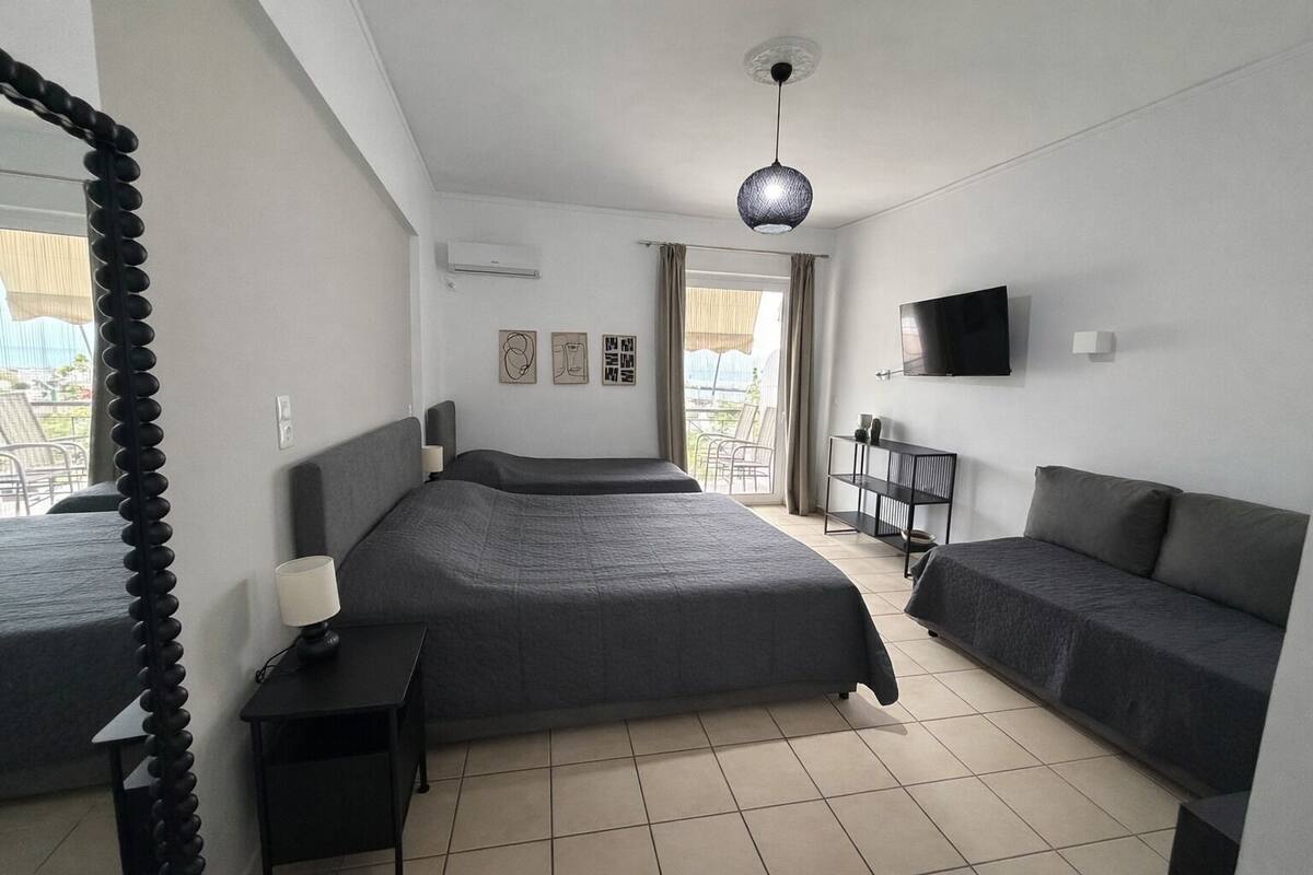 A hotel room with a large bed, a smaller bed, a TV, a desk, and a balcony view.