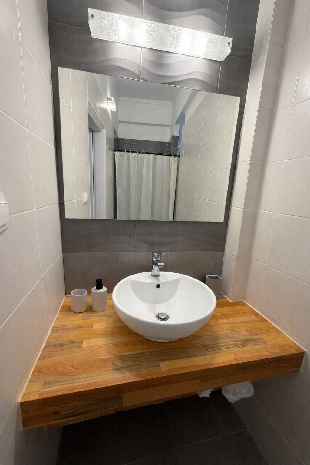 A bathroom with a white sink, wooden vanity, and a mirror.