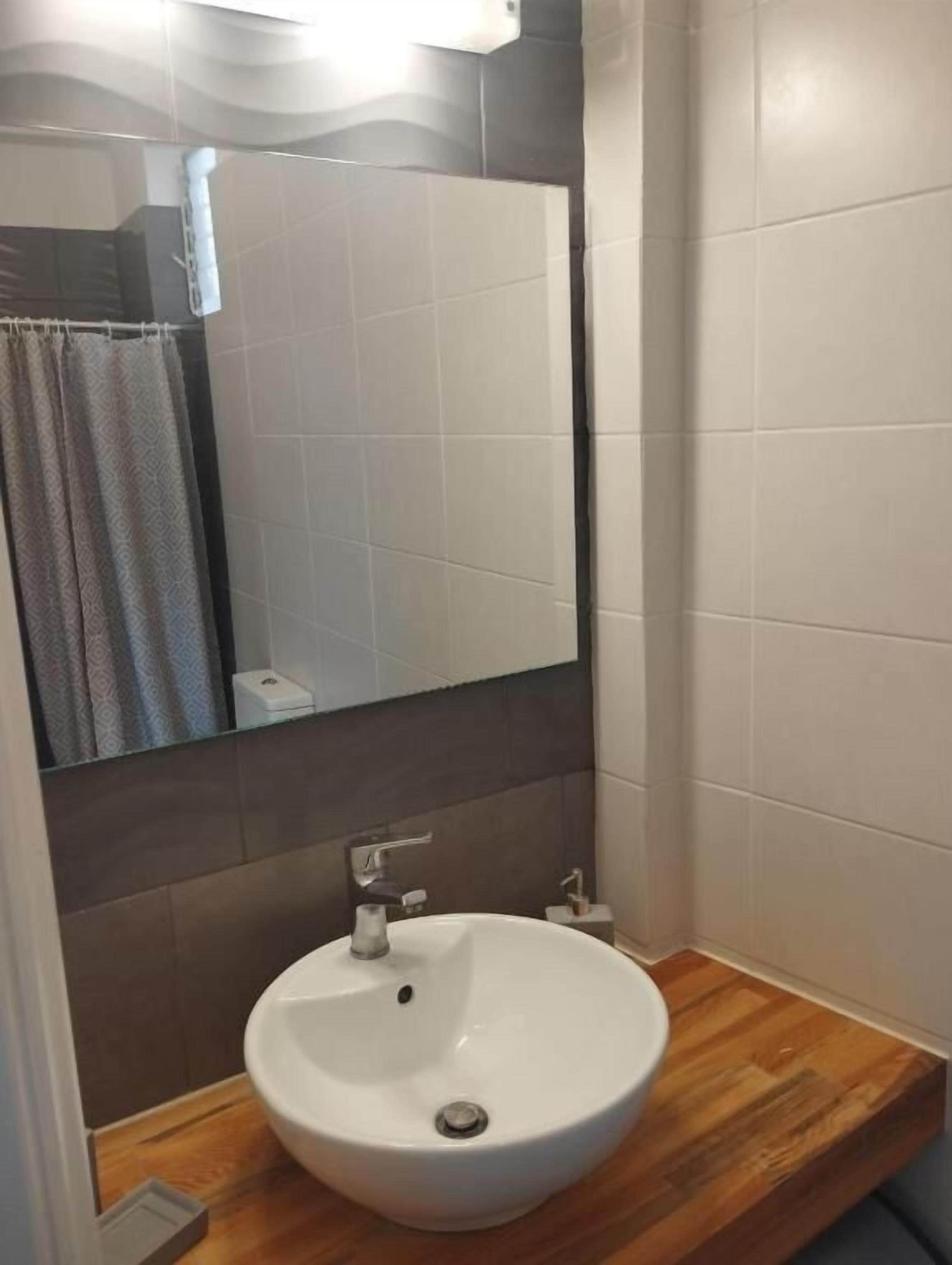 Un bagno con lavandino bianco, uno specchio e una tenda della doccia.