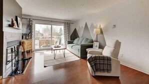 A modern living room with a sofa, armchair, and a fireplace. - La Place du Village (Magog)