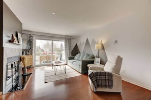 A modern living room with a sofa, armchair, and a fireplace. - La Place du Village (Magog)