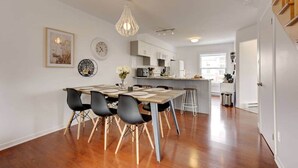 A modern kitchen with a dining area, wooden flooring, and a pendant light. - La Place du Village (Magog)