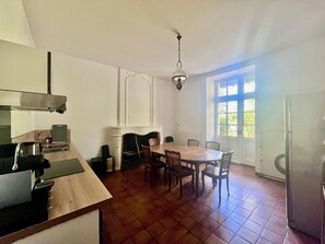 A kitchen with a dining table and chairs, a fireplace, and a window with a view of greenery. - Country house near Angoulême, 4 bedrooms (Torsac)