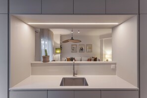 Een moderne keuken met een inbouwspoelbak, een potplant en een hanglamp.