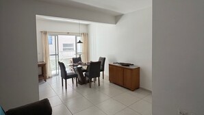 Ein modernes Wohnzimmer mit einer Couch, einem Esstisch, Stühlen und einem Schrank.
