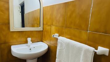 Une salle de bain avec un lavabo blanc, un miroir et un porte-serviettes.