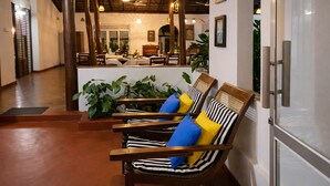 A lobby with wooden chairs, a reception desk, and indoor plants. - Habarana Inn - Offiacl (Habarana)