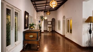 A hallway with a wooden dresser, potted plants, and hanging lamps. - Habarana Inn - Offiacl (Habarana)