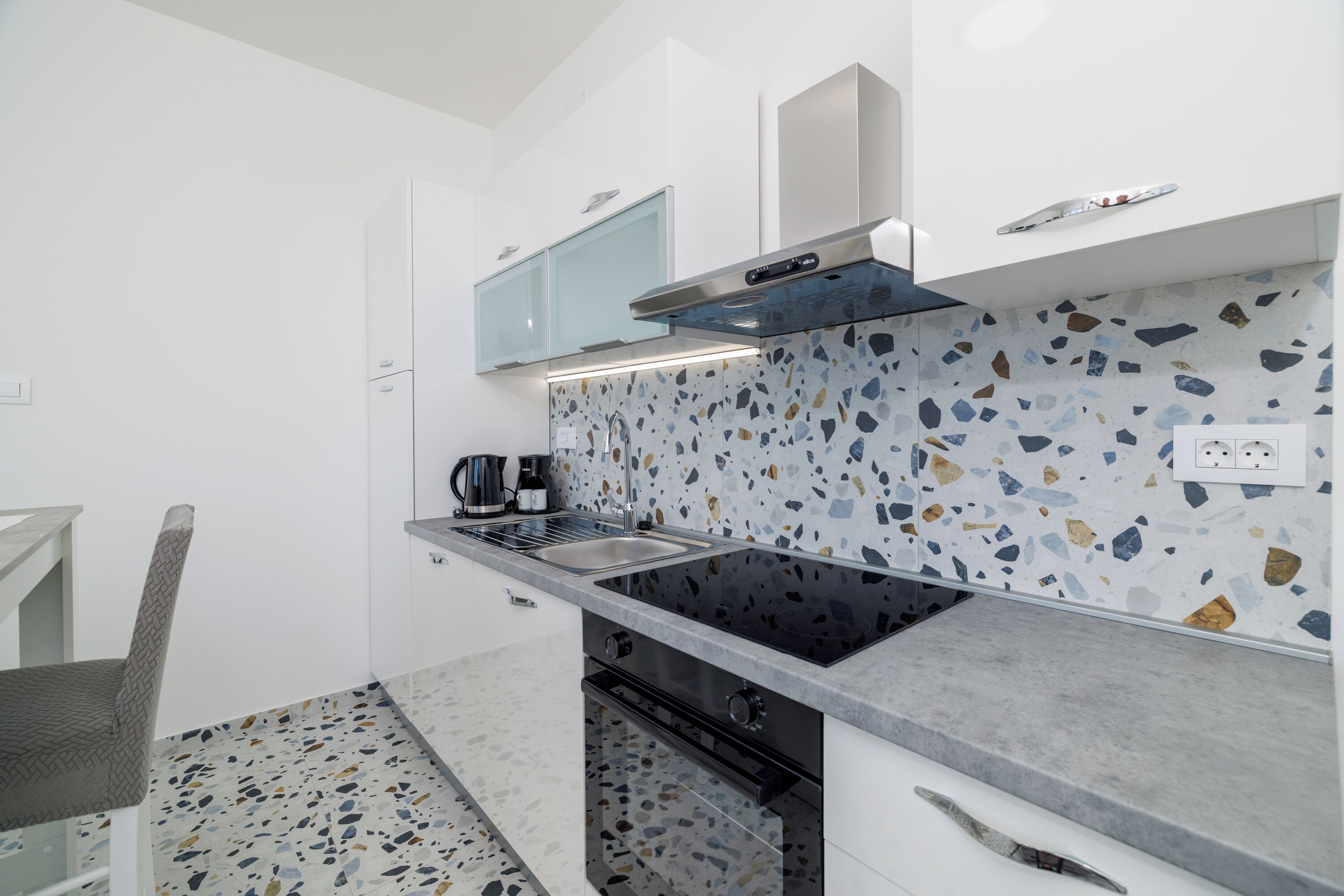 Una cocina moderna con encimera de granito, electrodomésticos de acero inoxidable y salpicadero con diseño moteado.