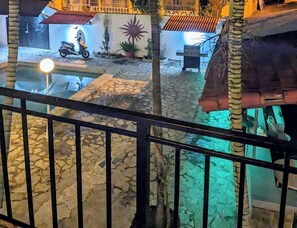 A courtyard with stone flooring, a scooter, a bench, and a wall with a sun design. - Peaceful In Playa Chiquita  (Sosúa)