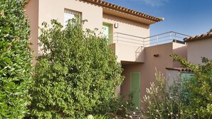Un edificio de dos pisos con un balcón, una puerta verde y una ventana.