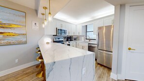 Eine moderne Küche mit einer Marmorinsel, Edelstahlgeräten und goldenen Akzenten.