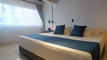 A modern bedroom with a large bed, a window with curtains, and a ceiling with wooden beams.