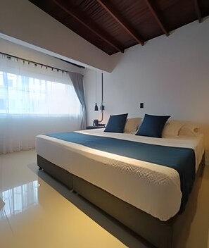 A modern bedroom with a large bed, a window with curtains, and a ceiling with wooden beams.