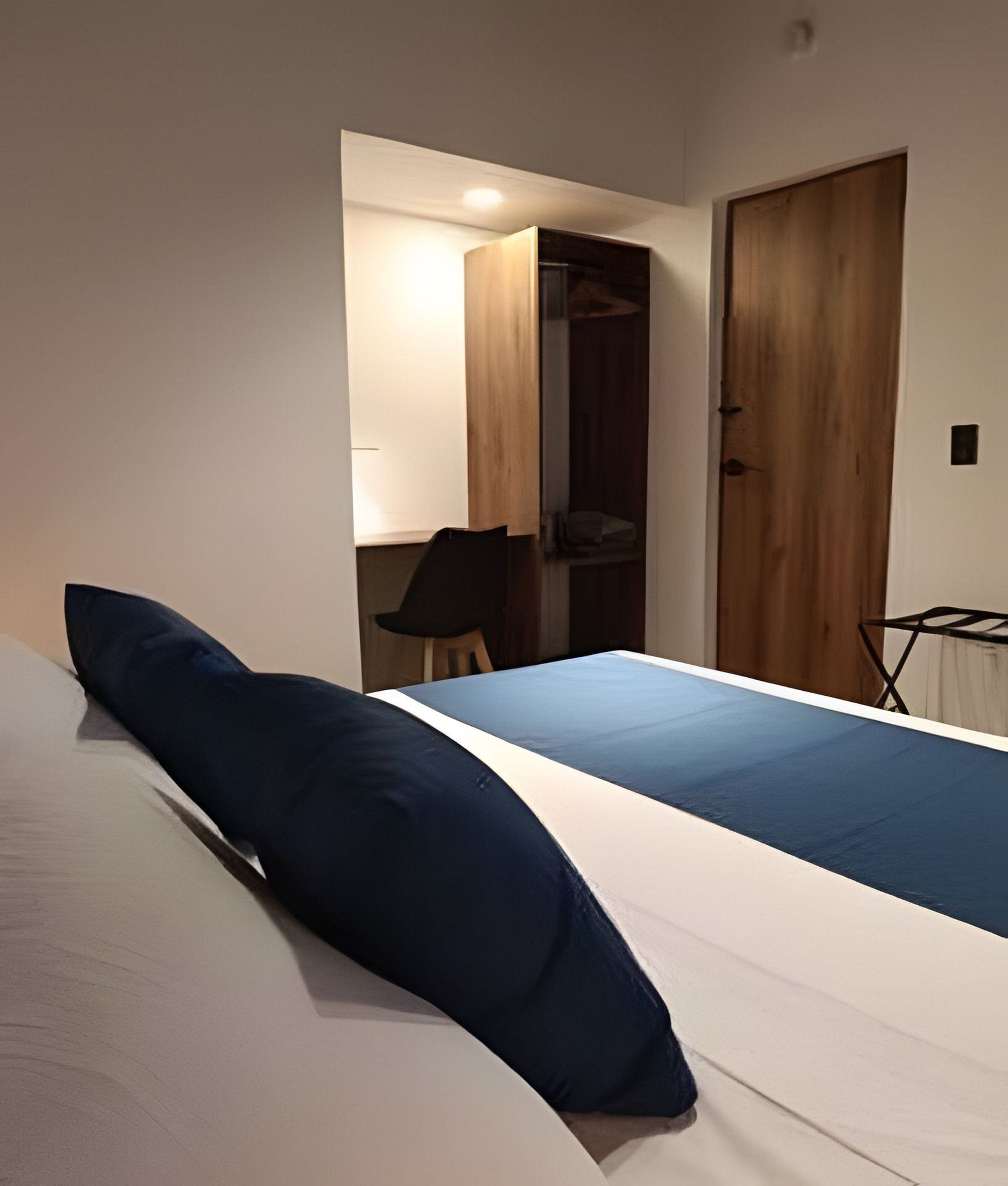A bedroom with a bed, a chair, and a wardrobe.