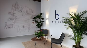 A modern interior with a large wall mural, a minimalist seating area, and a potted plant.