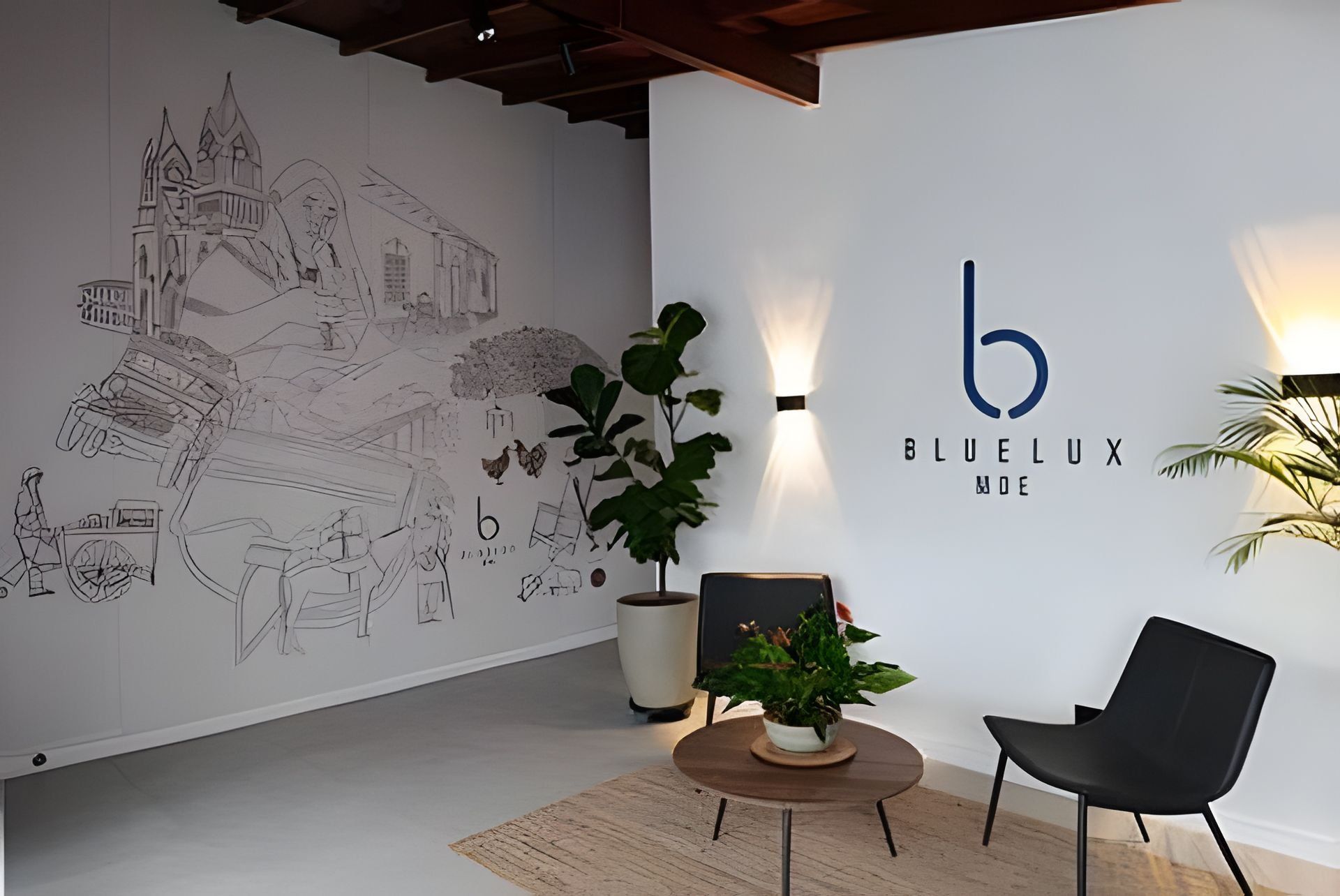 Een kamer met een groot wandtapijt, een ronde tafel met een potplant, een zwarte stoel en een wandlamp met het logo 'b BluLux'.